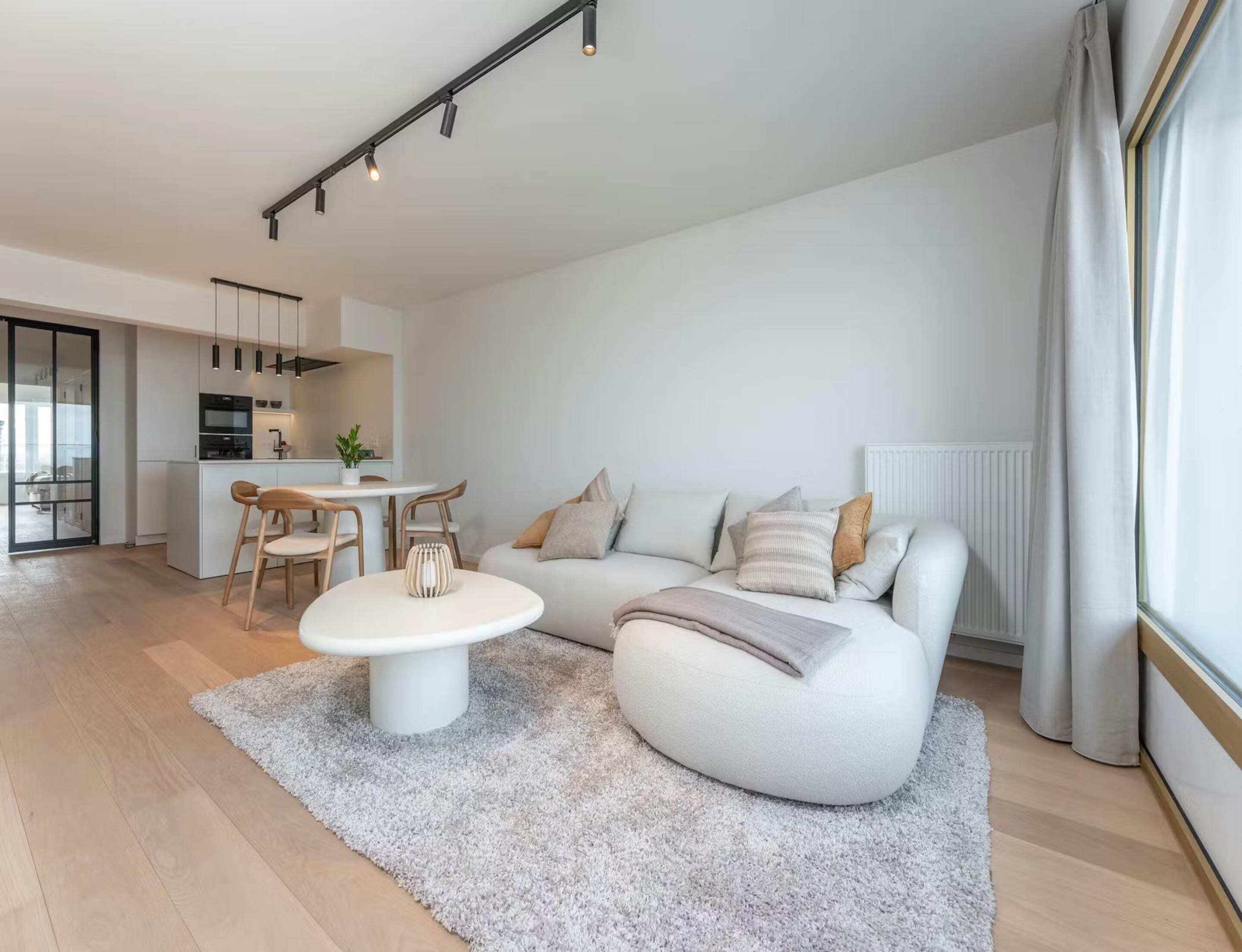 Una sala de estar moderna con un sofá, una mesa de centro y un comedor con sillas.