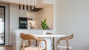 Una cocina moderna con armarios blancos, una isla central e iluminación colgante.