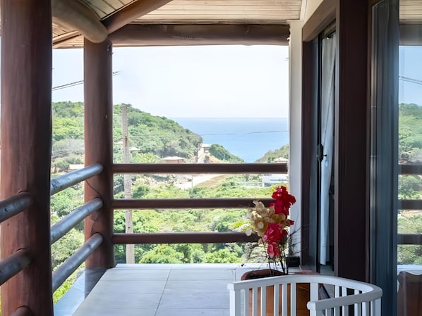 A balcony with a view of the sea, a white railing, and a potted plant with flowers. -  Pousada Ganesha Búzios (Buzios)