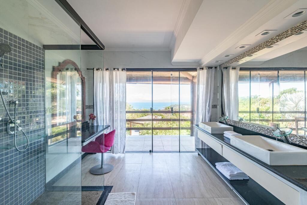 Un baño moderno con cabina de ducha de vidrio, un ventanal con vistas y un banco empotrado con espacio de almacenamiento.