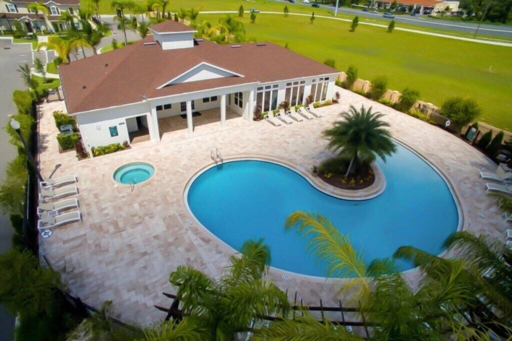 A large house with a swimming pool, a covered patio, and a lawn.