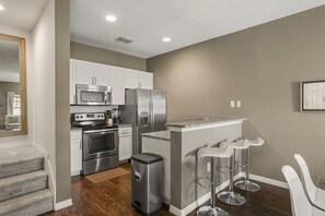 A modern kitchen with stainless steel appliances, a built-in oven, and a bar area with stools. - Modern Townhome 3 BD/ 2 BA/ West Lucaya (8980 SP) (Kissimmee)