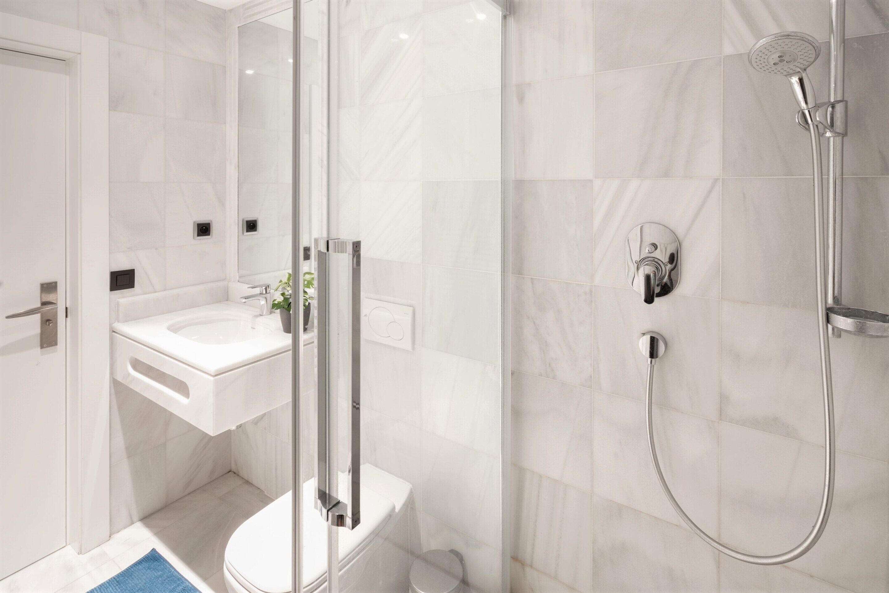 A modern bathroom with a glass shower enclosure, a white sink, and a toilet.