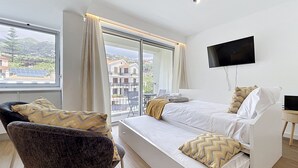 Une chambre d’hôtel moderne équipée d’un lit, d’une chaise, d’une télévision et d’un balcon avec vue.