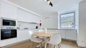 Une cuisine moderne avec des meubles blancs, une table à manger en bois et des chaises blanches.