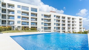 Un hôtel moderne doté d’une piscine, de nombreux balcons et offrant une vue sur un ciel d’un bleu éclatant.