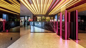 Eine moderne Hotelhalle mit einer Marmorrezeption, einer Glastrennwand und einer Decke mit linearer Beleuchtung.