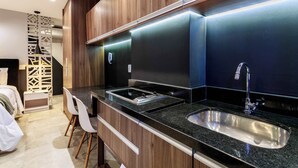 A modern kitchen with dark countertops, stainless steel sinks, and wooden cabinets. - Studio Completo a 5min do Metro V Olimpia | VG1703 (Vila Olímpia)