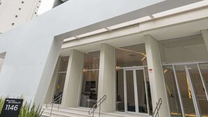 A modern building with a prominent entrance, large windows, and a staircase leading to the entrance. - Studio Completo a 5min do Metro V Olimpia | VG1703 (Vila Olímpia)