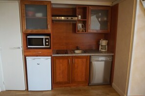 A compact kitchen with a microwave, refrigerator, dishwasher, and wooden cabinets. - 3-person apartment (Le Croisic)