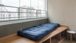 Una habitación con ventana, un banco, una pequeña mesa y vistas a edificios.