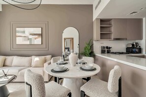 Een moderne eetruimte met een ronde tafel, witte stoelen en een minimalistische keuken op de achtergrond.