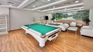 A pool table in a room with a sofa set, a television, and a mural of a landscape. - Spacious Studio Apartment that Sleeps 4 (JVC)