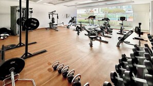 A gym with various exercise equipment, including weight machines, free weights, and cardio machines. - Spacious Studio Apartment that Sleeps 4 (JVC)