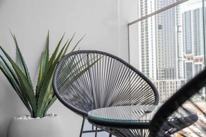 A modern chair, a potted plant, and a city view through a window. - Free housekeeping visits during your stay - StayShort - Modern Studio that Sleeps 4 at Riviera Beachfront (Meydan)
