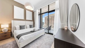 A modern bedroom with a large bed, a dresser, a mirror, and a view of a building through the window. - StayShort - Modern 1BR that Sleeps 4 at Riviera Beachfront (Meydan)