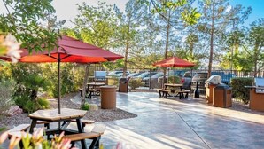 An outdoor patio area with picnic tables, red umbrellas, and barbecue grills. - Spacious 4-bedroom condo in peaceful Las Vegas with AC and gym (Las Vegas)