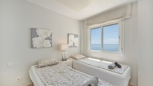 A bedroom with two beds, a window with a view, and artwork on the walls.
