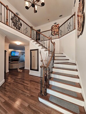 A grand staircase with a wooden finish and decorative railings, leading to an upper level. - 4 BEDROOM WORLD CUP FANS CLUBHOUSE FOR A  GROUP OR FAMILY OF 8+ (Duluth)