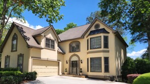 Une maison à deux étages avec un garage, une entrée principale dotée d’une porte et une allée.