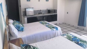 A hotel room with two beds, a kitchenette, a flat-screen TV, and a door leading to another room. - Macumba Hotel and Restaurant The best view of the Ria Lagartos. (Río Lagartos)