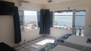 A room with two beds, a ceiling fan, and large windows overlooking a body of water. - Macumba Hotel and Restaurant The best view of the Ria Lagartos. (Río Lagartos)