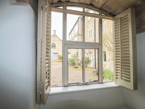 Ein Zimmer mit Fenster zum Innenhof, Holzboden und weißer Wand.