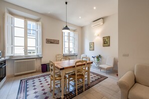 Ein Essbereich mit Holztisch und Stühlen, einem Heizkörper und einem Fenster mit geöffneten Fensterläden.