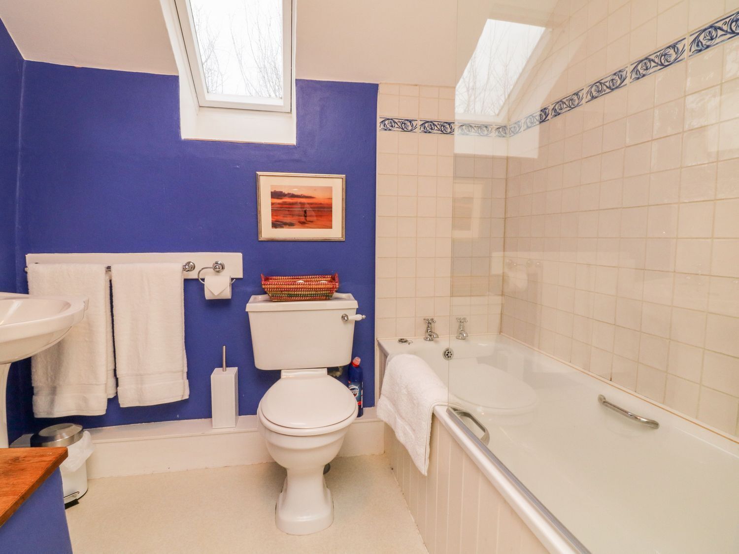 Un baño con inodoro, lavabo, bañera y tragaluz.
