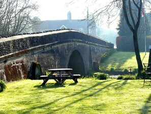 A stone bridge with an arch, a picnic table, and a grassy area with trees. - Whitefield Cottage (Barnstaple)