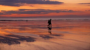 A beach at sunset with a person walking on the sand. - Whitefield Cottage (Barnstaple)