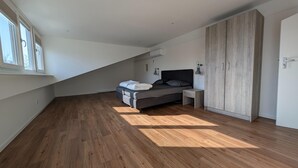 Un dormitorio con cama, mesita de noche, armario y ventana.