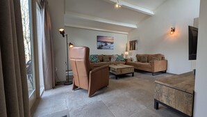 Una sala de estar moderna con un conjunto de sofá, una mesa de centro, un televisor y un cuadro en la pared.