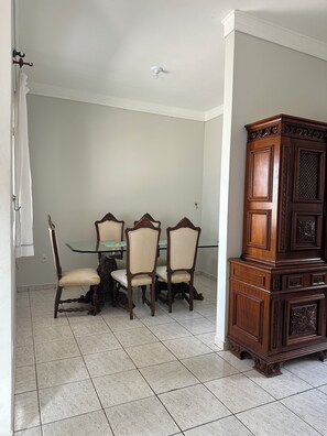 Een eetruimte met een glazen tafel en vier stoelen, een houten kast en een wit plafond.