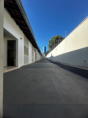 A long, straight corridor with white walls and a concrete floor, leading to a building with a blue-tinted window.. Billuca 2 Residential Complex