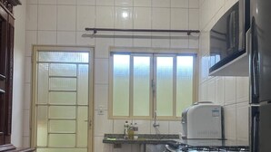Keittiössä on jääkaappi, liesi, mikroaaltouuni ja ikkuna, jossa on sälekaihtimet.
