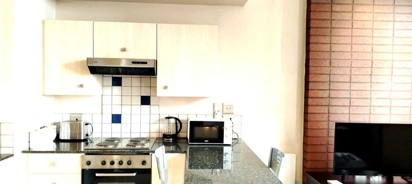 A kitchen with a stove, microwave, and a brick wall.