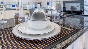 Een moderne keuken met lichte houten kastjes, een roestvrijstalen afzuigkap, een granieten aanrechtblad en een eethoek met een geweven placemat.