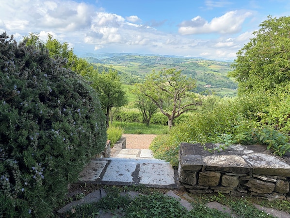 A stone pathway leading to a scenic overlook with a view of rolling hills and a clear sky.
