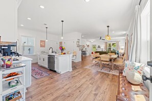 A spacious kitchen with white cabinetry, a central island, and a dining area with a wooden bench and chairs. - NEW BUILD | 10 Mins to Folly | 4 BR, 10 Guests (Charleston)