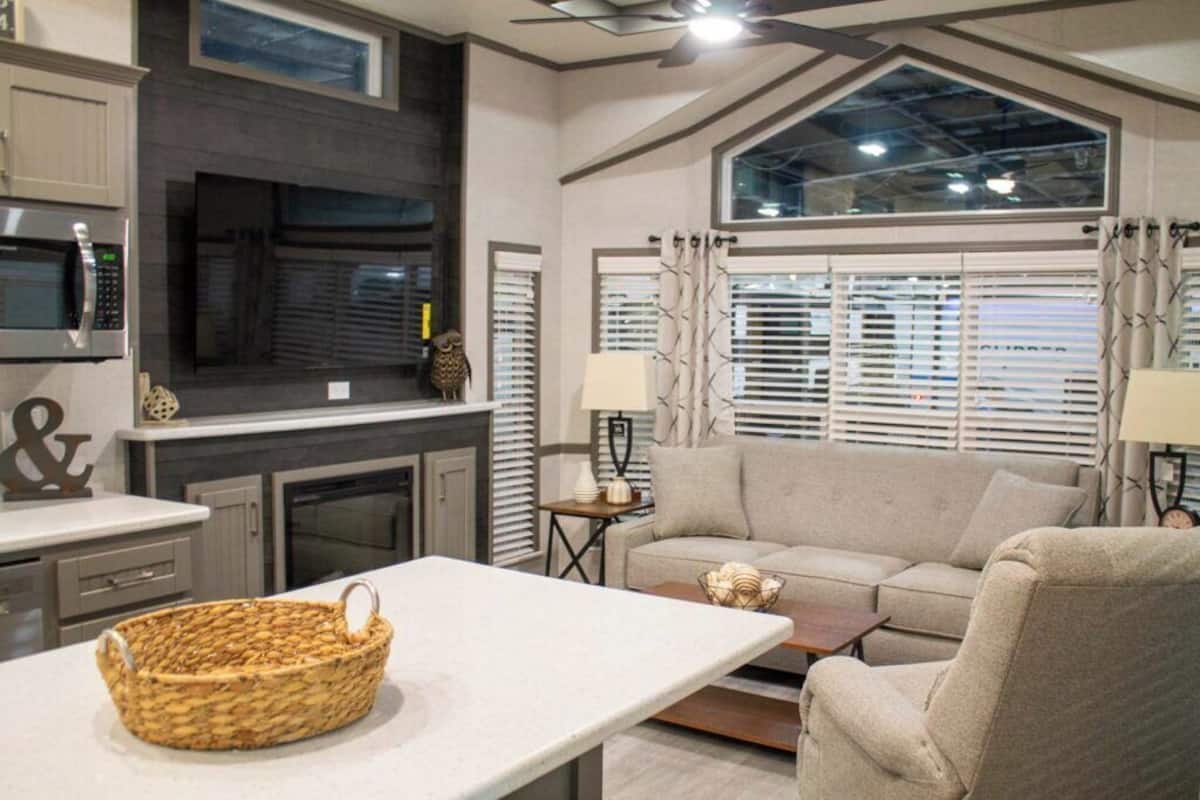 A modern kitchen with a microwave, cabinets, and a fireplace. There is a living area with a sofa and a coffee table.