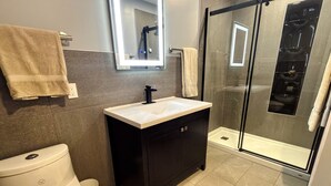 Un bagno con servizi igienici, lavandino, specchio e doccia.