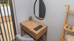 Een kamer met een houten bureau, een stoel, een spiegel en een kleine plant in een pot.