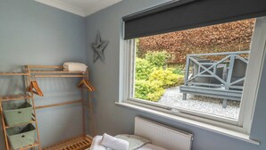 Een slaapkamer met een bed, een raam, ster decoratie en een houten plank met kledinghangers.