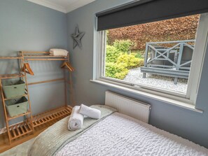 Ein Schlafzimmer mit einem Bett, einem Fenster, einer Sterndekoration und einem Holzregal mit Kleiderhängern.