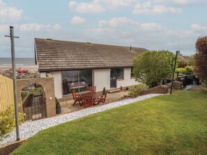 Ein Haus mit Terrasse, Esstisch und Blick auf den Strand.