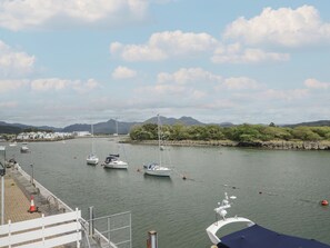 A marina with boats docked, a clear sky, and distant mountains. - The Boat Yard Apartment (Porthmadog)