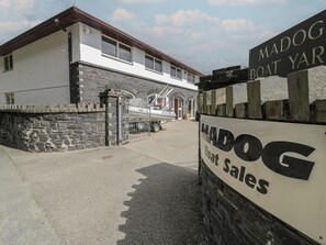 A building with a stone facade and a sign for 'MADOY BOAT SALES'. - The Boat Yard Apartment (Porthmadog)