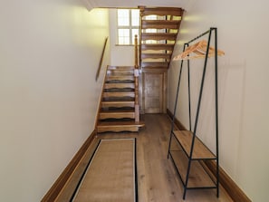 Eine Holztreppe mit einer Holztür am oberen Ende, einem Holzanzughalter und einem Holzboden.
