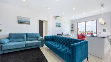 Ein modernes Wohnzimmer mit einem blauen Sofa, einem Essbereich mit einem roten Stuhl und einer Kücheninsel.
